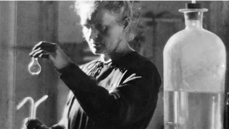 Photo de Marie Curie en train d'observer une fiole